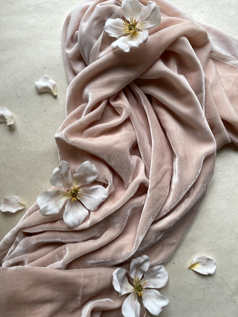 A draped pink velvet fabric with white flowers, symbolizing the emotional and sensory connections within fashion psychology.