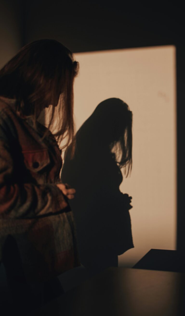 The Fear of Being Seen: A Strategic Guide for New Beginnings 5 A woman standing thoughtfully in a soft spotlight, representing the process of overcoming the fear of being seen through personal style and quiet confidence.