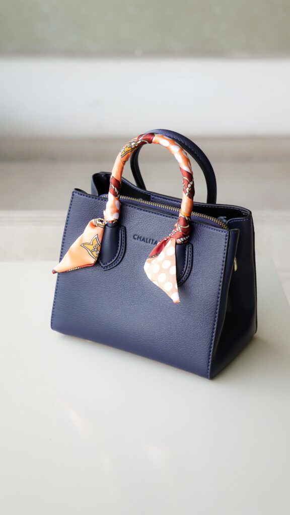  A minimalist, structured handbag on a clean background, an example of an accessory that helps you look expensive.