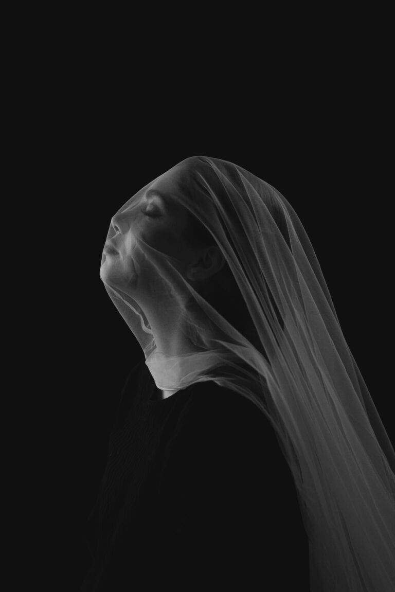 A woman looking through a textured veil, representing the barrier between self and society.