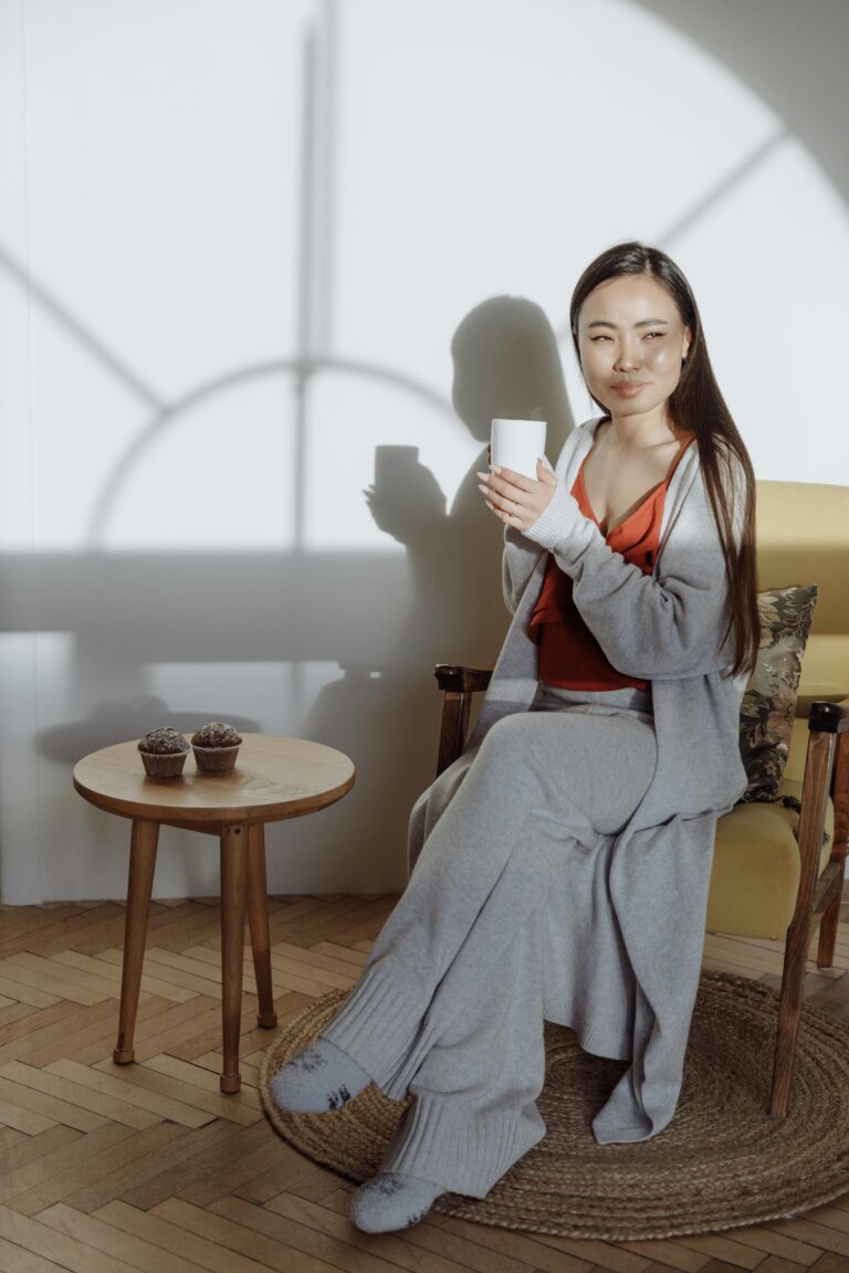 Soft-focus image of a minimalist co-ord loungewear set and two mugs, symbolizing restorative rest and low-energy style for Pyjama Day Self-Care.