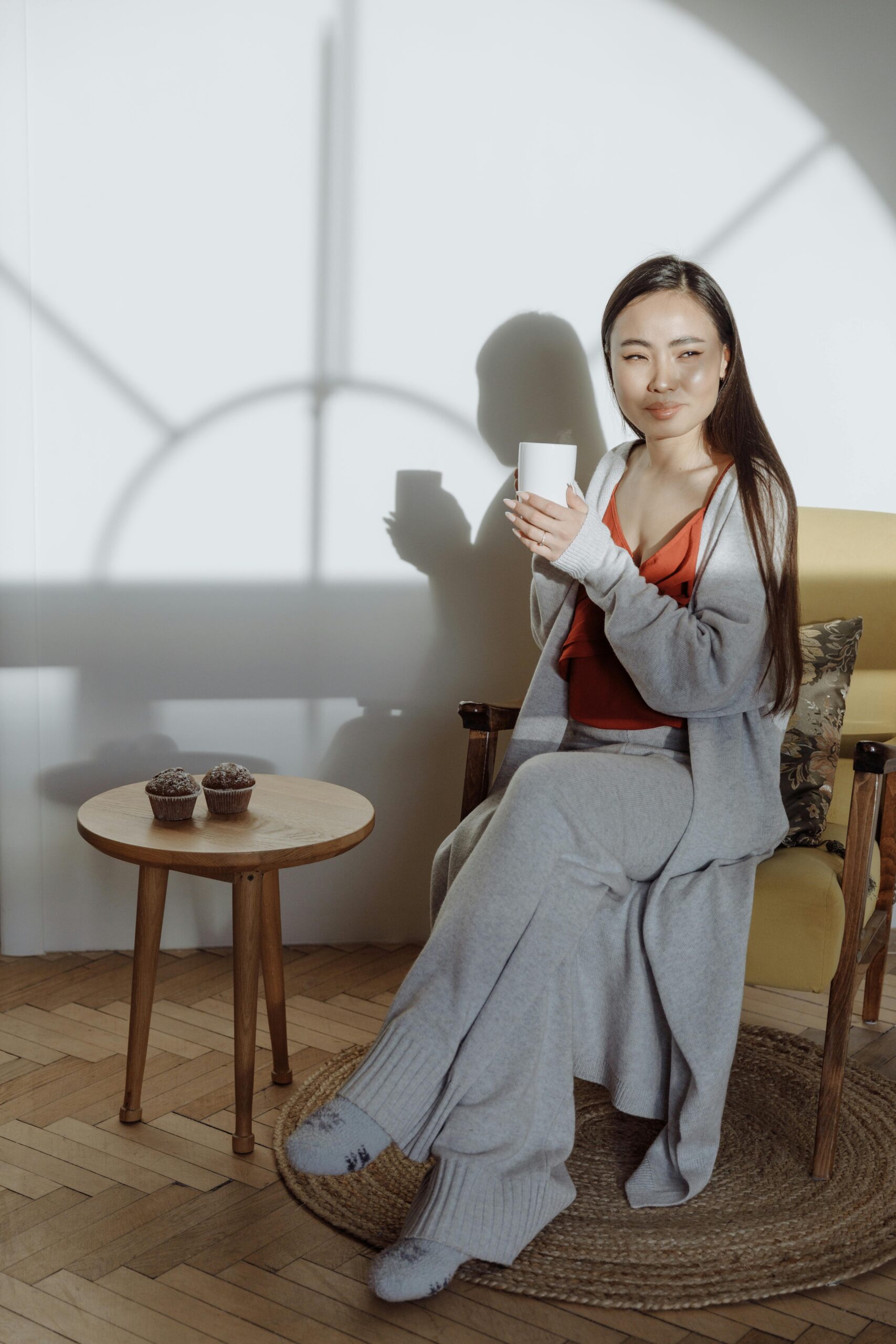 Soft-focus image of a minimalist co-ord loungewear set and two mugs, symbolizing restorative rest and low-energy style for Pyjama Day Self-Care.